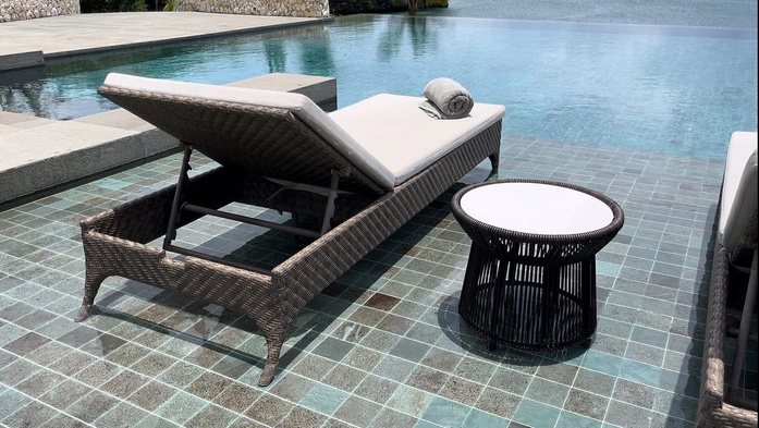 Woven sun lounger and side table by the pool