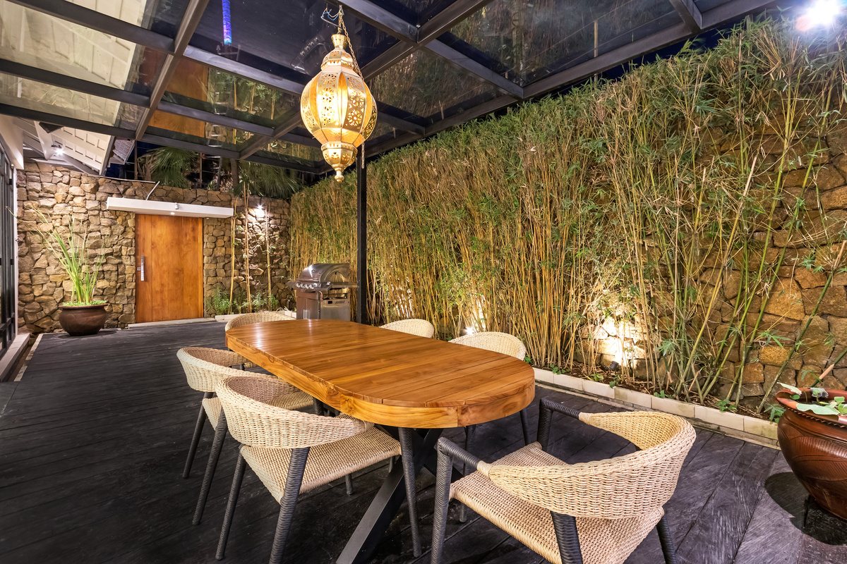 Oval timber dining table under a glass roof